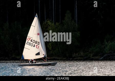 Una ragazza adolescente che guida un piccolo gommone a vela su Schluchsee nella Foresta Nera, Baden-Württemberg, Germania. Settembre. Foto Stock