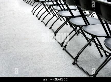 un gruppo di sedie pieghevoli vuote disposte in fila in una sala conferenze. Foto Stock