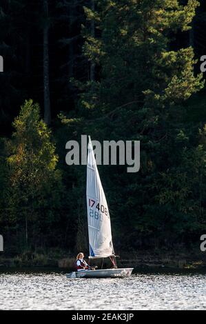 Una ragazza adolescente che guida un piccolo gommone a vela su Schluchsee nella Foresta Nera, Baden-Württemberg, Germania. Settembre. Foto Stock