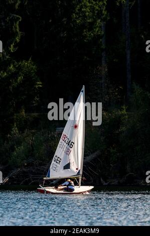 Una ragazza adolescente che guida un piccolo gommone a vela su Schluchsee nella Foresta Nera, Baden-Württemberg, Germania. Settembre. Foto Stock