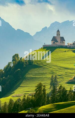 Paesaggio montano con villaggi di Colle Santa Lucia con chiesa in Dolomiti, Alto Adige, Italia Foto Stock