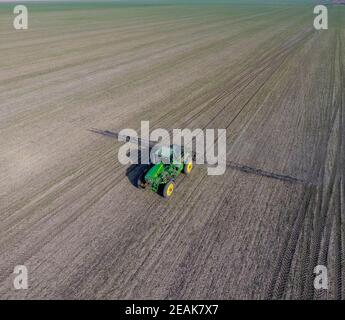 Trattore con sistema incernierato di irrorazione di pesticidi. Concimazione con un trattore, sotto forma di aerosol, sul campo del grano invernale. Foto Stock