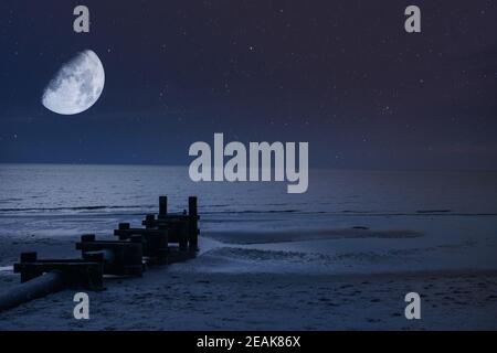 Una Mezza Luna e Stelle sulla Spiaggia e l'Oceano Di notte con un tubo Foto Stock