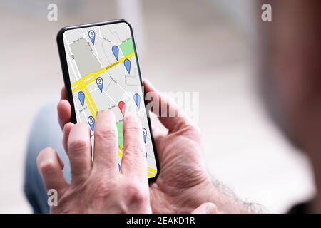 Mano della persona che utilizza la mappa di navigazione GPS Foto Stock