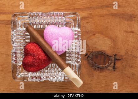 Amore e abitudine dannosa in un posacenere di vetro Foto Stock