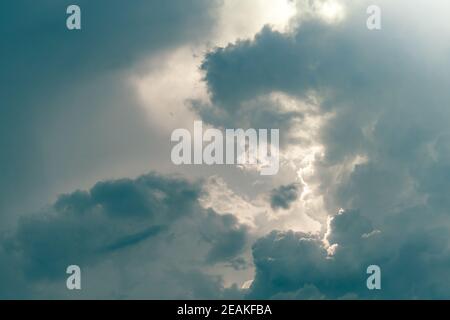 Cielo grigio e nuvole soffici con luce solare. Cielo nuvoloso. Sfondo per la morte e il concetto triste. Cielo triste e umoroso. Natura sfondo. Paesaggio nuvoloso. Speranza nel giorno delle tenebre. Cielo sovrastato. Luce del sole dietro le nuvole Foto Stock