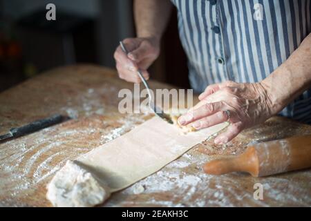 Tipico dessert di Natale delle asturie. Mani di donna anziana mettendo il ripieno di nocciole sulla pasta fatta in casa per casadielle. Gastronomia Foto Stock