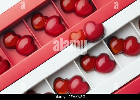 Crea caramelle al cioccolato fondente in una doppia forma a doppio cuore rosso in scatole. Modello. Dolce regalo per il giorno delle valentine Foto Stock