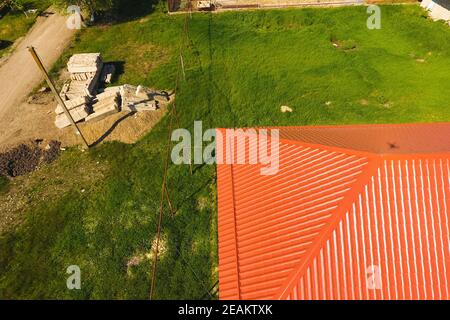 Casa con un tetto arancione di metallo, vista dall'alto. Profilo metallico dipinto corrugato sul tetto. Foto Stock