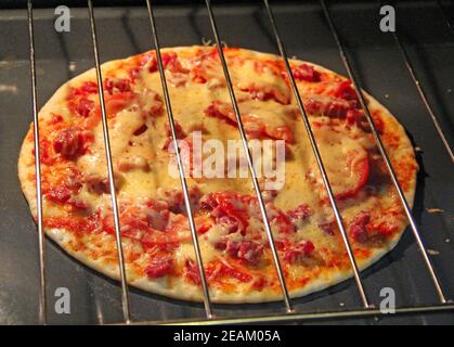 Cuocere nel forno per preparare una deliziosa pizza. Cucina fast food nel ristorante Foto Stock