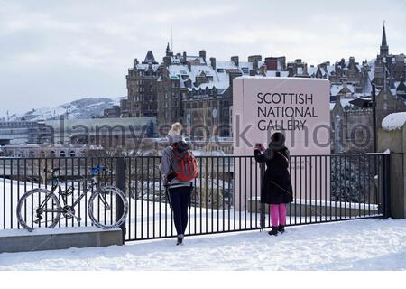 Edimburgo, Scozia, Regno Unito. 10 febbraio 2021. Una notte in pieno centro lascia il tumulo coperto di neve. I visitatori che fotografano i giardini di Princes Street alla Scottish National Gallery con vista sui tetti innevati della città vecchia. Credit: Craig Brown/Alamy Live News Foto Stock