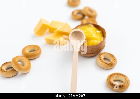 miele in una ciotola di legno, bagel e formaggio su sfondo bianco Foto Stock