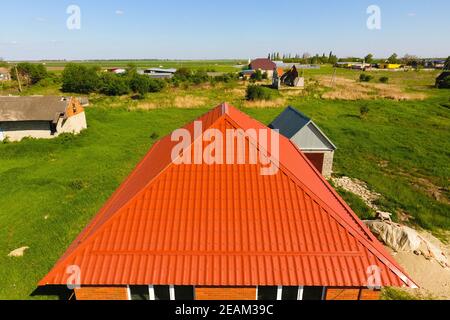 Casa con un tetto arancione di metallo, vista dall'alto. Profilo metallico dipinto corrugato sul tetto. Foto Stock