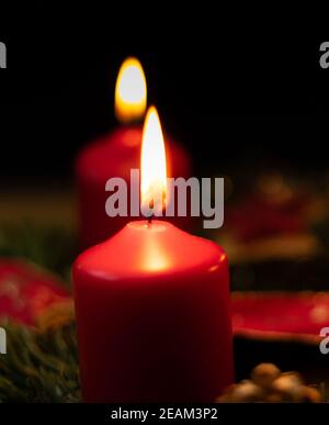 la candela rossa dell'avvento brucia sulla corona di natale Foto Stock