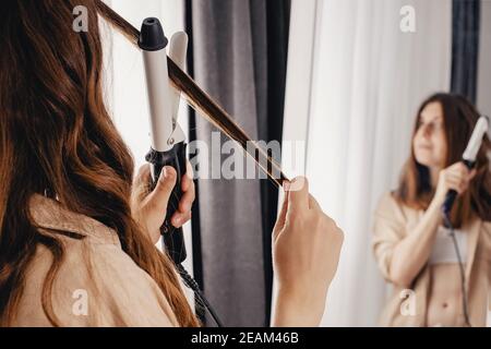 Giovane donna che piega i suoi capelli lunghi e luminosi marroni Foto Stock