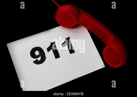 Chiamata 911 e concetto di chiamata di emergenza, testo 911 su carta e telefono isolato su nero. Foto Stock