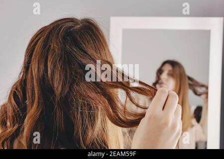 Giovane donna che piega i suoi capelli lunghi e luminosi marroni Foto Stock