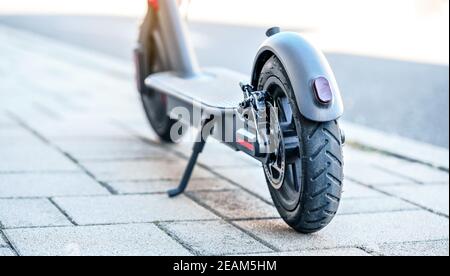 Scooter elettrico parcheggiato su pavimenti in pietra piastrellata - dettaglio primo piano sulla ruota posteriore Foto Stock