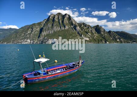 Una barca sul Lago d'Iseo, le montagne di Corna Trentapassi sull'altro lato del lago. Lombardia, Italia. Foto Stock