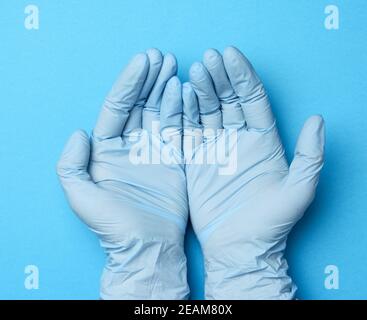 due mani femminili in guanti di lattice blu, palme da medico su sfondo blu, vista dall'alto Foto Stock