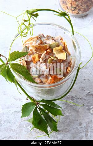 Granola con yogurt in un bicchiere trasparente su sfondo chiaro. Cibo sano a basso contenuto calorico. Prodotto naturale. Cibo vegetariano. Foto verticale. Foto Stock