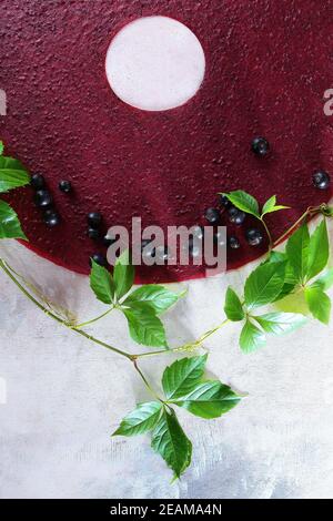 Pastila ribes nero su sfondo chiaro. Un ramo di luppolo con foglie verdi nelle vicinanze. Foto verticale. Concetto di vita still. Foto Stock