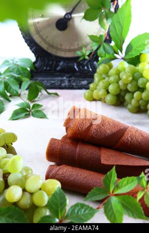 La dolcezza dell'uva brillante. Bioprodotto naturale senza conservanti. Cibo per vegetariani. Grappoli di uva su sfondo chiaro. Scale vintage sullo sfondo. Foto Stock