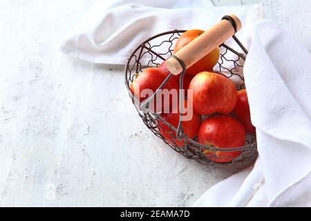 Mele rosse in un cestello di metallo su uno sfondo chiaro. Prodotto naturale. Cibo vegetariano. Tovagliolo bianco. Foto Stock