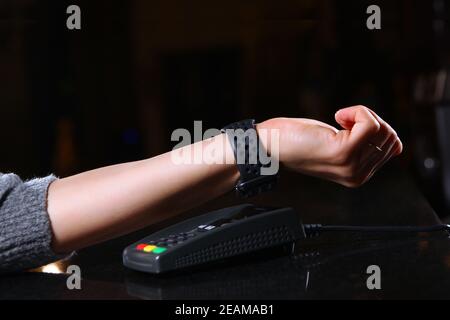 Pagamento tramite orologio da polso tramite terminale in un ristorante o negozio. Mano femminile primo piano con un orologio quando si paga per un acquisto. Spazio di copia. Foto Stock