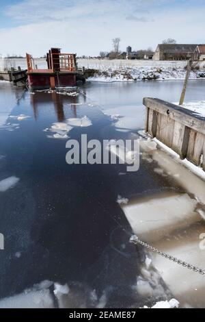 Bici e traghetto pedonale Ruterpolder Fr37 sopra il Geeuw in IJlst, Frisia nei Paesi Bassi in inverno con ghiaccio sul canale e lago Foto Stock