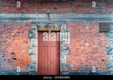 Buchi bullet in una facciata casa dalla seconda guerra mondiale Rustico, muro di mattoni rossi con porte Foto Stock