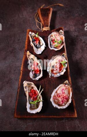 Due tipi di ostriche con salse salate su tavola di legno. Elegante servizio di piatti. Stagione Oyster. Foto irriconoscibile. Primo piano. Foto Stock