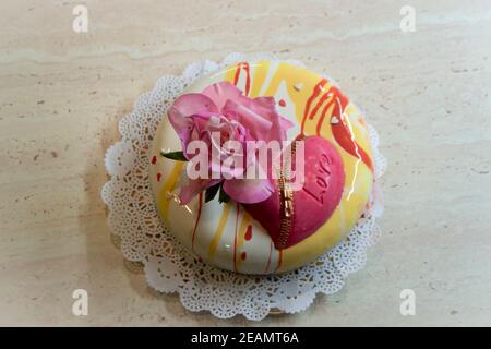 torta mousse con cuore di cioccolato decorato con rosa commestibile. Fiore fondente Foto Stock