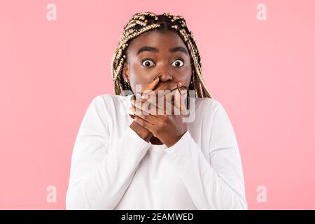 Sorprende la giovane afroamericana che ricopre la bocca con le mani Foto Stock