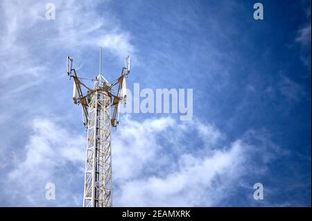 particolare di una torre metallica con antenne di comunicazione telefonica, radio e tv su un cielo blu e nuvoloso Foto Stock