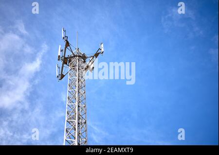 particolare di una torre metallica con antenne di comunicazione telefonica, radio e tv su un cielo blu e nuvoloso Foto Stock