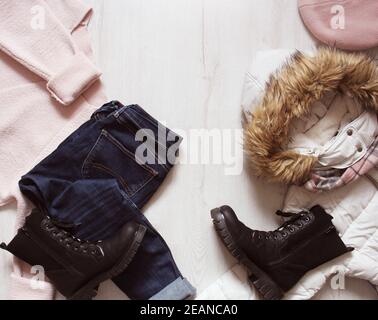 Un set di moda inverno abiti da donna. Maglione di lana, scarpe, jeans, rivestire, cappello e sciarpa sul bianco sullo sfondo di legno. Foto Stock