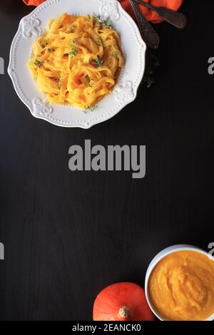 Tagliatelle con crema di zucca salsa sopra lo sfondo nero.vista superiore Foto Stock