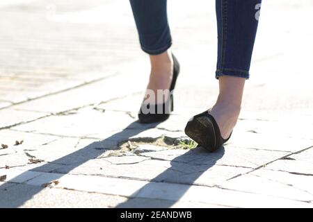 Gambe donna con tacchi alti che si stacciano la caviglia in strada Foto Stock