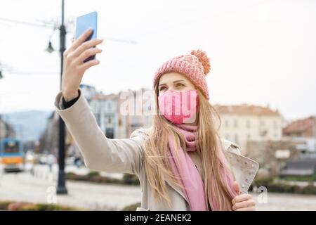 Donna che indossa la maschera corona facendo selfie con il telefono Foto Stock