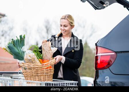 Donna che carica i generi alimentari dopo lo shopping nel tronco della sua auto Foto Stock