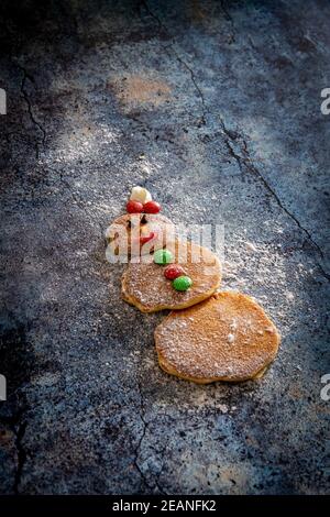 Carino frittelle decorate a forma di pupazzo di neve su sfondo tavolo fatto da bambini per Natale, Italia, Europa Foto Stock