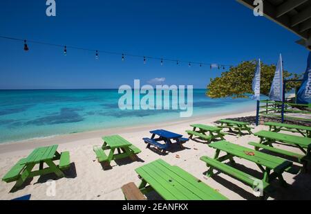 Grand Cayman Beach Deck Sedie ombrelloni blu sul bordo dell'acqua, Isole Cayman, Grand Cayman, Seven Mile Beach - Isole Cayman, sfondi, Spiaggia Foto Stock