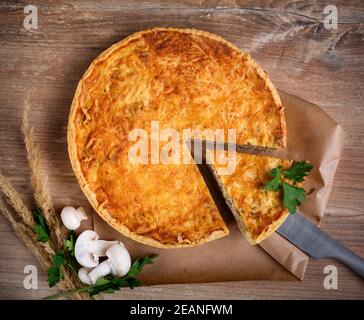 Crostata fatta in casa con pasta sfoglia con funghi, formaggio, cipolla, prezzemolo e aneto su rustico tavolo di legno. Vista dall'alto. Foto Stock