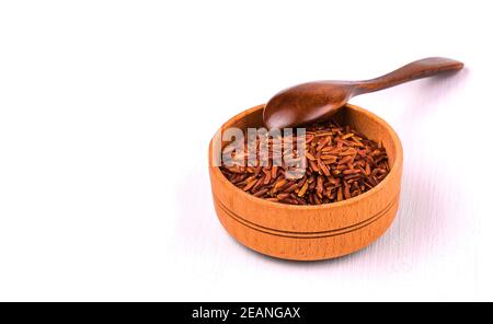 Il riso marrone in una tazza di legno su un tavolo da pranzo bianco. Foto Stock