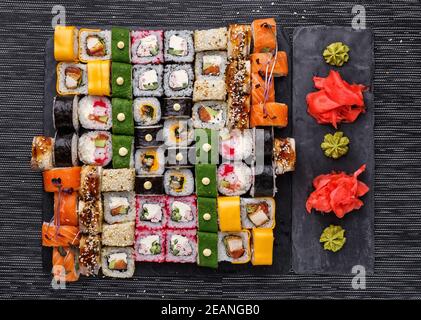Cucina giapponese. Sushi con ingredienti freschi su sfondo nero. Diversi tipi di ruoli. Foto Stock