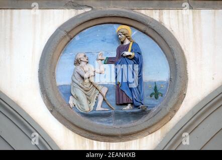 Opere di Misericordia, terracotta invetriata tondo di Andrea della Robbia, situata tra due archi del vecchio Ospedale di San Paolo, a Firenze, Italia Foto Stock