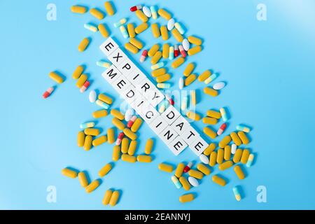 La parola della DATA DI SCADENZA MEDICINALE con la pillola su blu Sfondo Foto Stock