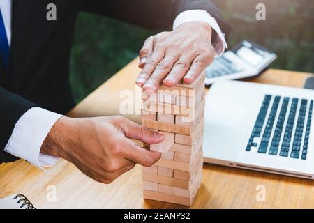 Uomo d'affari rischio gioco tirare legno blocco sulla scrivania ufficio Foto Stock