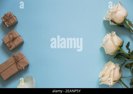 rose bianche e regali da carta artigianale su sfondo blu. Buon San Valentino o Festa della mamma. Foto Stock